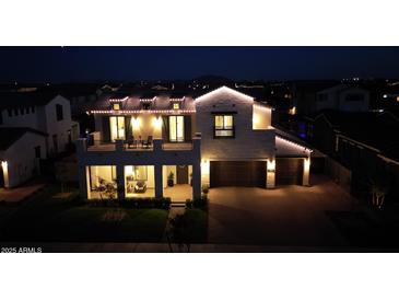 Striking two-story home illuminated at night, featuring a spacious balcony and a two-car garage at 3669 E Boot Track Trl, Gilbert, AZ 85296