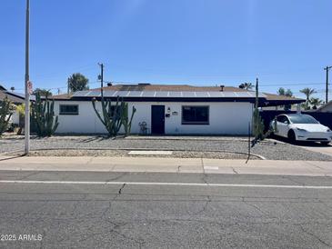 Charming single-story home with a desert landscape, solar panels, and a modern vehicle parked nearby at 5607 N 23Rd Ave, Phoenix, AZ 85015