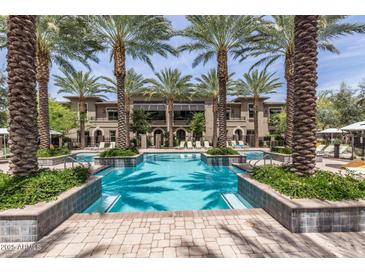 Resort-style pool surrounded by lush landscaping, palm trees, and plenty of seating for relaxation at 6565 E Thomas Rd # 1128, Scottsdale, AZ 85251