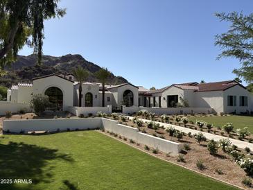 Stunning exterior of white home featuring tile roof, manicured lawn and lush landscaping at 7501 N Eucalyptus Dr, Paradise Valley, AZ 85253