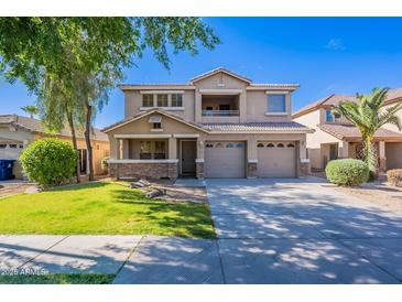 Inviting two-story home featuring a three-car garage, charming balcony, and a well-manicured front yard at 10517 W La Reata Ave, Avondale, AZ 85392
