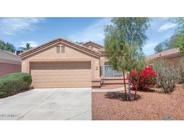 Single-story home featuring a two-car garage, desert landscaping, and a tile roof at 12450 W Hearn Rd, El Mirage, AZ 85335