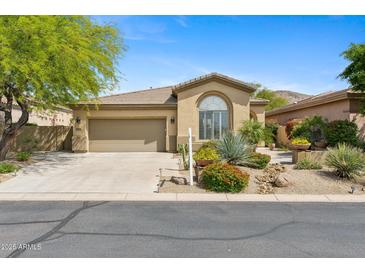Charming home featuring a tan exterior, desert landscaping, and an attached two-car garage at 15037 N 114Th Way, Scottsdale, AZ 85255
