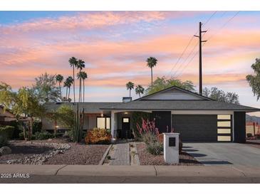 Charming single-story home with desert landscaping, palm trees, and a modern dark gray two-car garage at 8730 E Montecito Ave, Scottsdale, AZ 85251