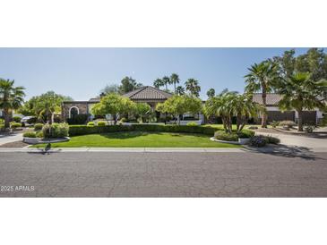 Beautiful single-story home with manicured lawn, mature trees, and a circular driveway with a neutral color scheme at 12820 N 83Rd Pl, Scottsdale, AZ 85260