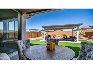 Outdoor living space boasts an extended covered patio, artificial turf, and a well-maintained landscape at 27636 W Runion Dr, Buckeye, AZ 85396
