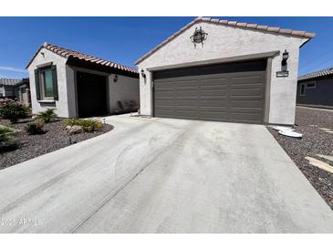 Home with a two-car garage, desert landscaping, and a concrete driveway at 27636 W Runion Dr, Buckeye, AZ 85396