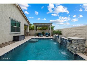 A refreshing pool offers beautiful waterfalls and a pergola with seating, creating a perfect backyard oasis at 9834 E Thatcher Ave, Mesa, AZ 85212