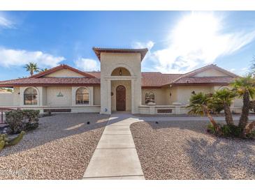 Inviting home featuring a well-manicured yard, tiled roof, and a charming arched entryway at 12899 W Pasadena Ave, Litchfield Park, AZ 85340