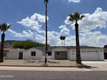 Charming single-story home featuring a two-car garage, palm trees, and desert landscaping at 1423 W Joan De Arc Ave, Phoenix, AZ 85029