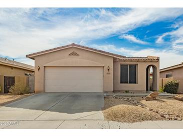 Tan single-story home featuring a two-car garage, desert landscaping, and an arched entryway at 15134 N 138Th Ln, Surprise, AZ 85379