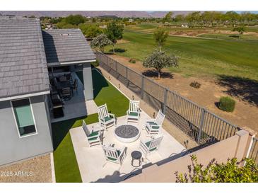 Lush backyard featuring an outdoor kitchen and cozy fire pit area with picturesque views of the adjacent golf course at 17362 W Wildwood St, Surprise, AZ 85388