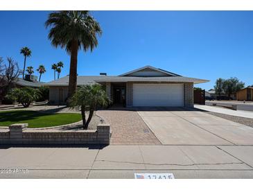 Charming single-story home featuring a well-manicured lawn, brick accents, and a two-car garage at 17415 N 57Th Ave, Glendale, AZ 85308