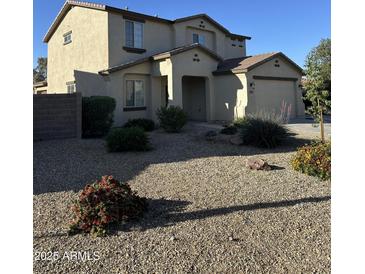 Inviting two-story home featuring a neutral color scheme, a two-car garage, and low maintenance desert landscaping at 17681 W Molly Ln, Surprise, AZ 85387