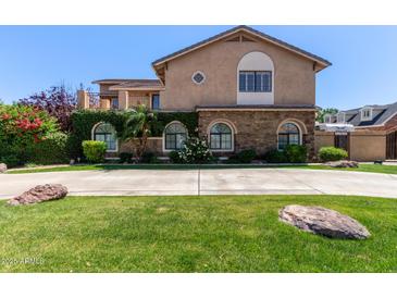 Beautiful two-story home with a stone facade, lush landscaping, and arched windows at 3203 E Ellis St, Mesa, AZ 85213