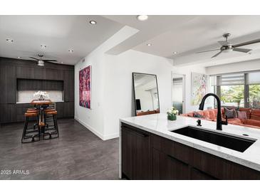 Modern kitchen with sleek, dark cabinetry, white countertops, a breakfast bar and stainless steel appliances at 7167 E Rancho Vista Dr # 4010, Scottsdale, AZ 85251
