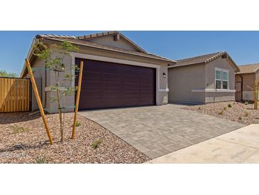 Attached garage features a dark brown door, stone driveway, desert landscaping, and taupe stucco at 25319 N 131St Dr, Peoria, AZ 85383