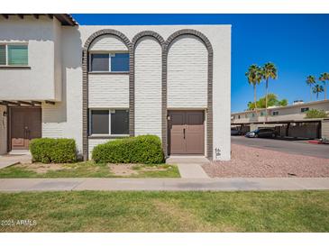 Charming townhouse featuring unique arched brickwork and a well-maintained front lawn at 7647 E Montecito Ave, Scottsdale, AZ 85251
