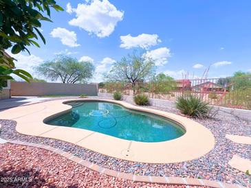 Backyard pool with stone border, landscaping and blue skies at 1248 W Deoni Trl, San Tan Valley, AZ 85143