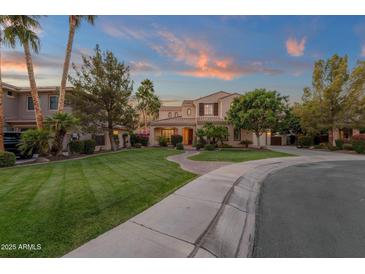 Elegant two-story home featuring lush landscaping, mature trees, and a curved walkway leading to the entrance at 1356 E Flamingo Ct, Gilbert, AZ 85297