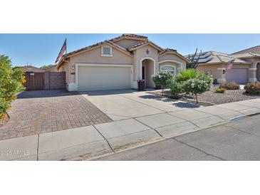 Charming single-story home featuring a two-car garage, desert landscaping, and an American flag at 15731 W Redfield Rd, Surprise, AZ 85379