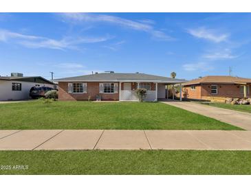 Charming brick home features a well-manicured lawn, classic white trim, and an attached carport for convenient parking at 1944 W Osborn Rd, Phoenix, AZ 85015