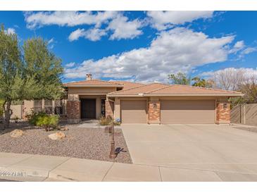 Beautiful single-story home with a tile roof, desert landscaping and a spacious three car garage with brick detailing at 104 E Louis Way, Tempe, AZ 85284