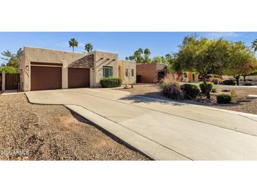 Charming home featuring a stucco facade, desert landscaping, and a spacious driveway leading to a two-car garage at 1554 E Kings Ct, Gilbert, AZ 85234