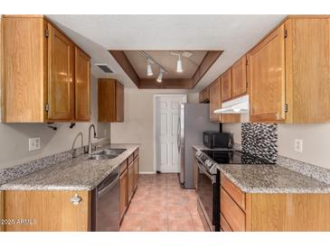 Traditional kitchen featuring granite countertops, stainless steel appliances, and warm wood cabinets at 1976 N Lemon Tree Ln # 16, Chandler, AZ 85224