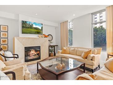 Comfortable living room featuring a fireplace, plush seating, and large windows at 2402 E Esplanade Ln # 204, Phoenix, AZ 85016