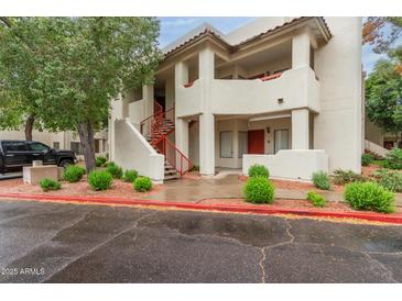 Multi-level condo building featuring well maintained landscaping and white stucco facade with red accents and covered entryways at 750 E Northern E Ave # 2145, Phoenix, AZ 85020