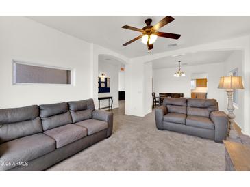 Comfortable living room with neutral carpet, a ceiling fan, and modern design details at 10539 W Tamara Dr, Casa Grande, AZ 85193