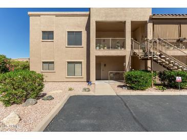 Two-story condo with a beige exterior, front porch, exterior stairs, and desert landscaping at 13805 N Hamilton Dr # H102, Fountain Hills, AZ 85268