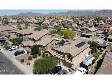 Expansive aerial view of a well-maintained community with mountain views and houses equipped with solar panels at 22022 W Moonlight Path, Buckeye, AZ 85326
