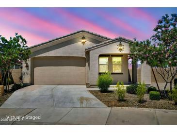 Charming single-story home with a well-maintained lawn and a two-car garage, all under a beautiful sunset sky at 5956 N 188Th Ln, Litchfield Park, AZ 85340