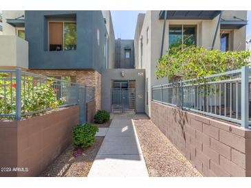 Inviting walkway leading to a gated front entrance surrounded by green landscaping and modern architecture at 615 E Portland St # 261, Phoenix, AZ 85004