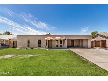 Charming single-story home with a well-manicured lawn and light brickwork against a bright blue sky at 908 S Kachina --, Mesa, AZ 85204