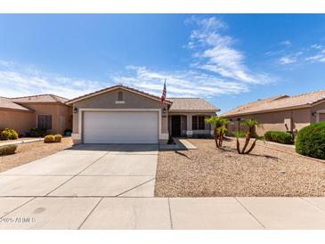 Charming single-story home with desert landscaping, a two-car garage, and an American flag at 15047 W Kings Dr, Surprise, AZ 85374