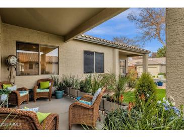 Inviting covered patio space with wicker furniture and lush landscaping, perfect for outdoor relaxation and entertaining at 23705 S Pleasant Way, Sun Lakes, AZ 85248