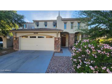 Charming front exterior featuring a stone-accented two-car garage, manicured landscaping, and welcoming front door at 29740 N 121St Ave, Peoria, AZ 85383