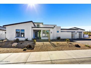 Stunning modern home featuring a sleek white exterior, desert landscaping, and a three car garage at 3335 W Desert Dawn Dr, Phoenix, AZ 85083
