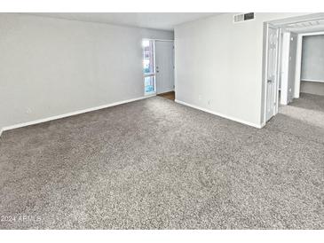 Spacious, carpeted living room with neutral walls and ample natural light coming from the front door at 3810 N Maryvale Pkwy # 1070, Phoenix, AZ 85031