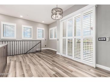 Bright living room boasts wood-look tile floors, neutral walls, shuttered windows and sliding doors to a balcony at 42424 N Gavilan Peak Pkwy # 24206, Anthem, AZ 85086