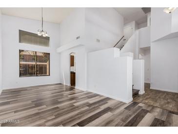 Open-concept living room with tall ceilings, wood-look floors, and stairs leading to the second floor at 8037 W Mohave St, Phoenix, AZ 85043