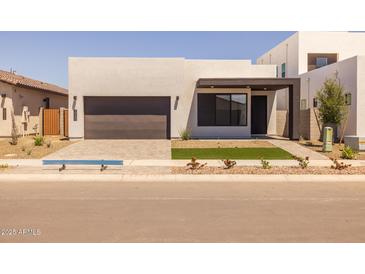 Modern home featuring a minimalist design, a dark brown garage door, and low maintenance landscaping at 10230 E Utah Ave, Mesa, AZ 85212