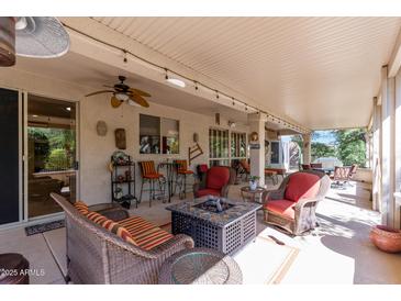 Inviting covered patio featuring comfortable seating, fire pit, and ceiling fan for outdoor relaxation at 15797 W Cinnabar Dr, Surprise, AZ 85374