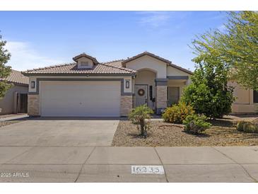 Charming single-story home featuring a tile roof, a two-car garage, and well-maintained desert landscaping at 16235 W Cottonwood St, Surprise, AZ 85374