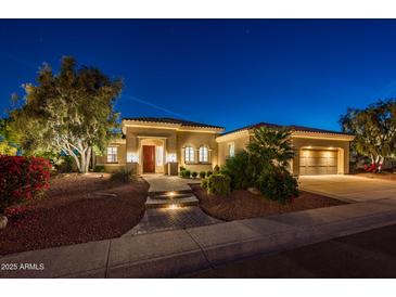 Inviting single-story home with manicured landscaping and illuminated walkway leading to a red front door at 22208 N San Ramon Dr, Sun City West, AZ 85375