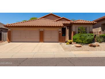 Inviting single-story home boasting a desert landscaped front yard, a terracotta tile roof, and a convenient three-car garage at 22232 N 48Th St, Phoenix, AZ 85054