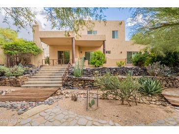This two-story home boasts a covered patio, stone stairs, desert landscaping, and a view of the natural terrain at 39017 N Habitat Cir, Cave Creek, AZ 85331